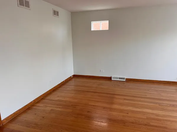 a view of an empty room with wooden floor and a ceiling fan