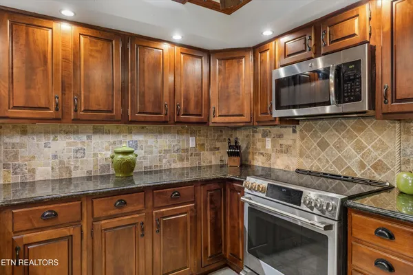 a kitchen with granite countertop a stove sink and microwave