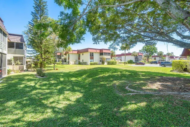 a view of a house with a big yard and large trees