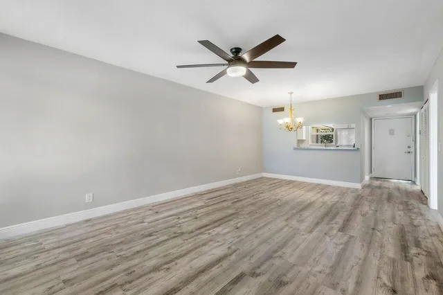 a view of an empty room with wooden floor and a ceiling fan