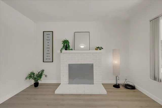 a living room with a fireplace and potted plant