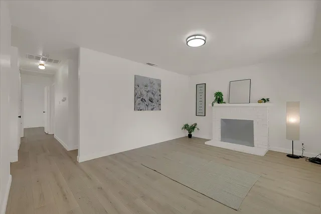 a view of empty room with wooden floor and a fireplace