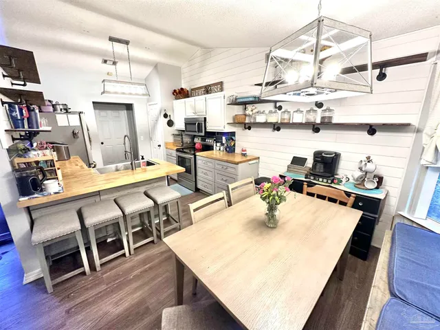 a room with stainless steel appliances kitchen island granite countertop a table chairs and a stove