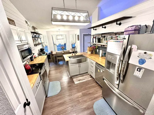 a dining room with stainless steel appliances kitchen island granite countertop a table chairs and a wooden floor