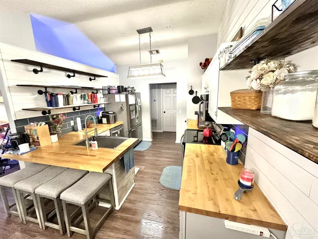 a kitchen with stainless steel appliances granite countertop a refrigerator a stove and a sink with wooden floor