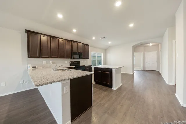 a kitchen with kitchen island granite countertop a sink and a stove top oven