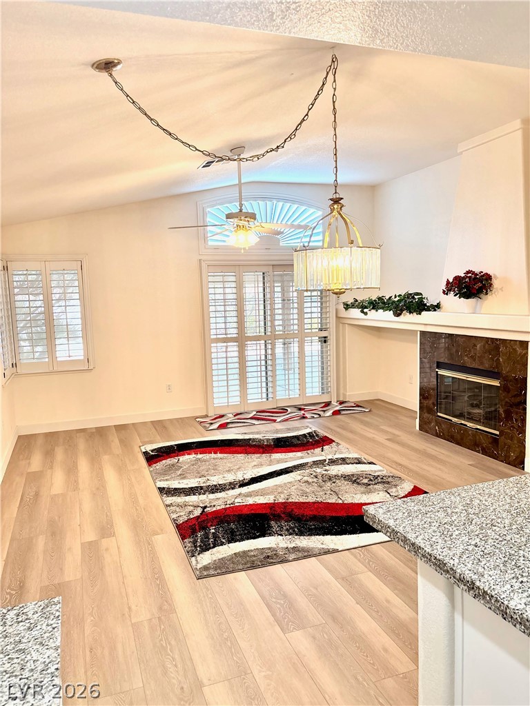 9040 Dove River Road Las Vegas, NV 89134 - Photo 7 of 22 An inviting living space with warm wood-style flooring, a marble-surrounded fireplace, and vaulted ceilings.