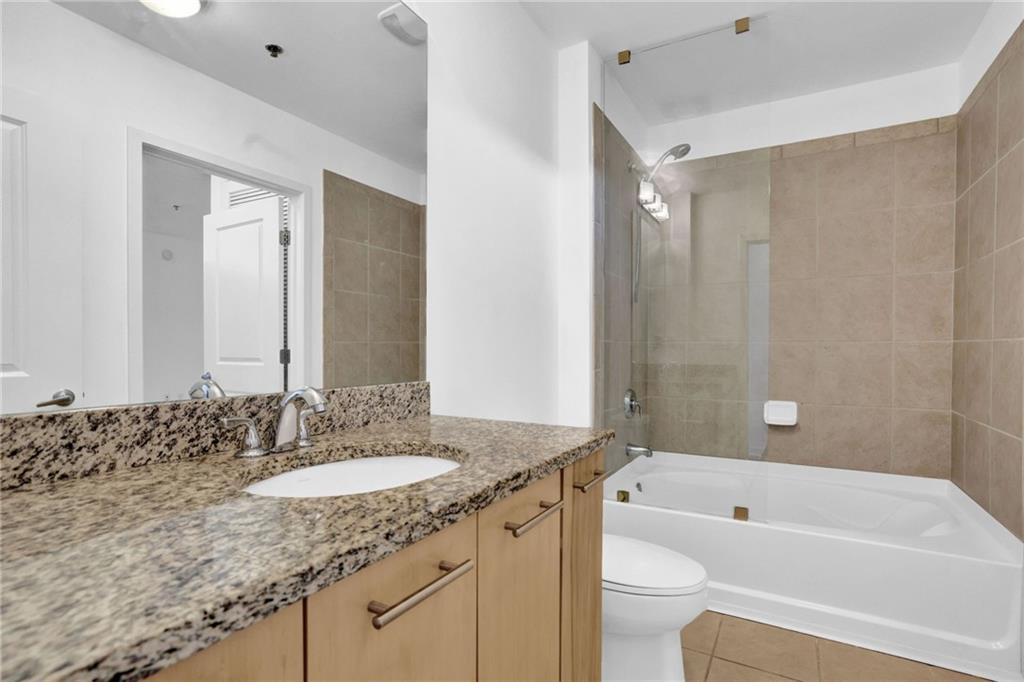 3324 Peachtree Road Northeast, Unit 2507 Atlanta, GA 30326 - Photo 15 of 25 a bathroom with a granite countertop sink a toilet a mirror a bathtub and shower