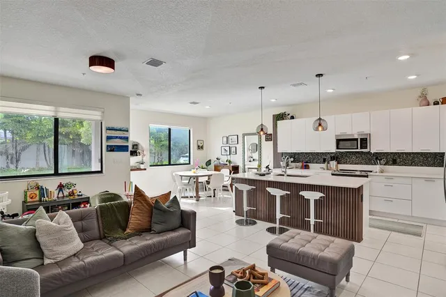 a living room with furniture kitchen view and a large window