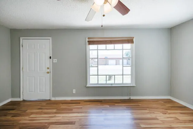 an empty room with wooden floor and windows