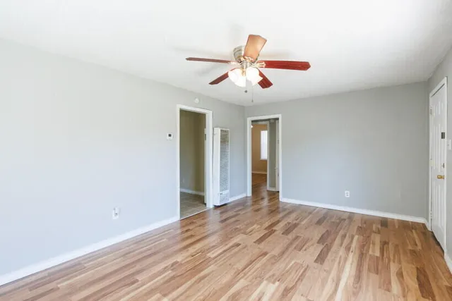 an empty room with wooden floor and windows