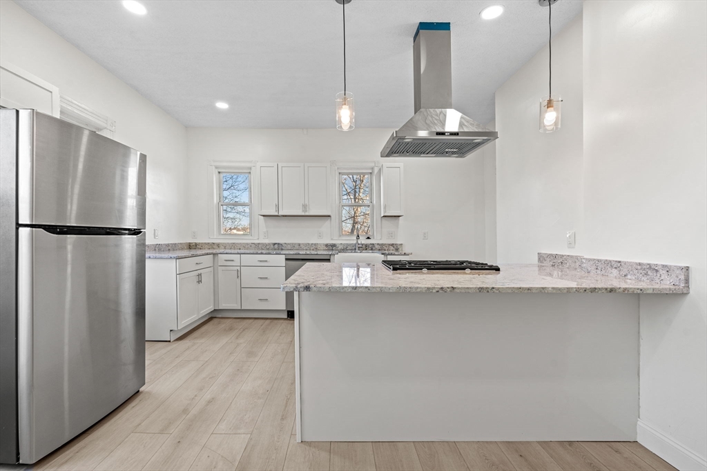 36 Elm Hill Park, Unit 1F Boston, MA 02121 - Photo 5 of 23 a kitchen with stainless steel appliances a refrigerator a sink dishwasher a stove and white cabinets with wooden floor