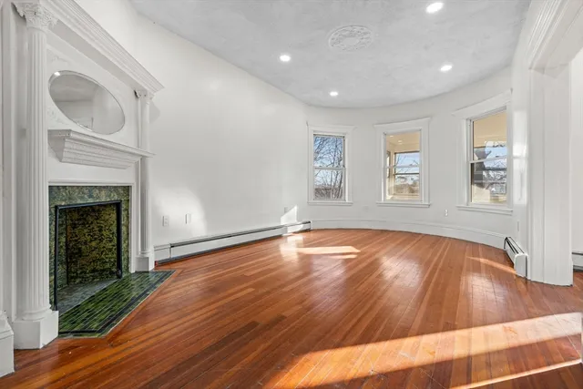 a view of empty room with wooden floor and fireplace