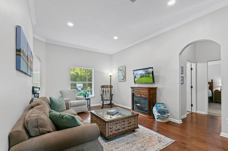 2724 North Portofino Road St. Augustine, FL 32092 - Photo 17 of 86 Living area with arched walkways, dark wood-type flooring, a glass covered fireplace, crown molding, and recessed lighting