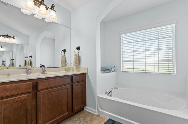 2724 North Portofino Road St. Augustine, FL 32092 - Photo 26 of 86 Bathroom with vanity, a garden tub, and light tile patterned flooring