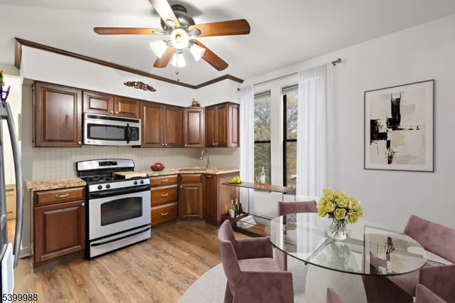 a kitchen with stainless steel appliances granite countertop a stove top oven a sink dishwasher a dining table and chairs with wooden floor