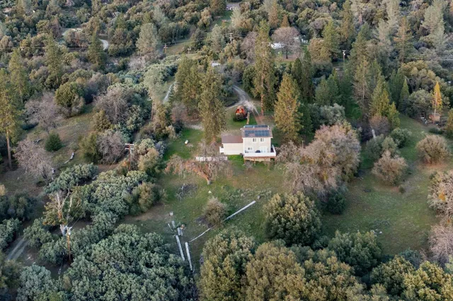 an aerial view of residential house with outdoor space and trees all around