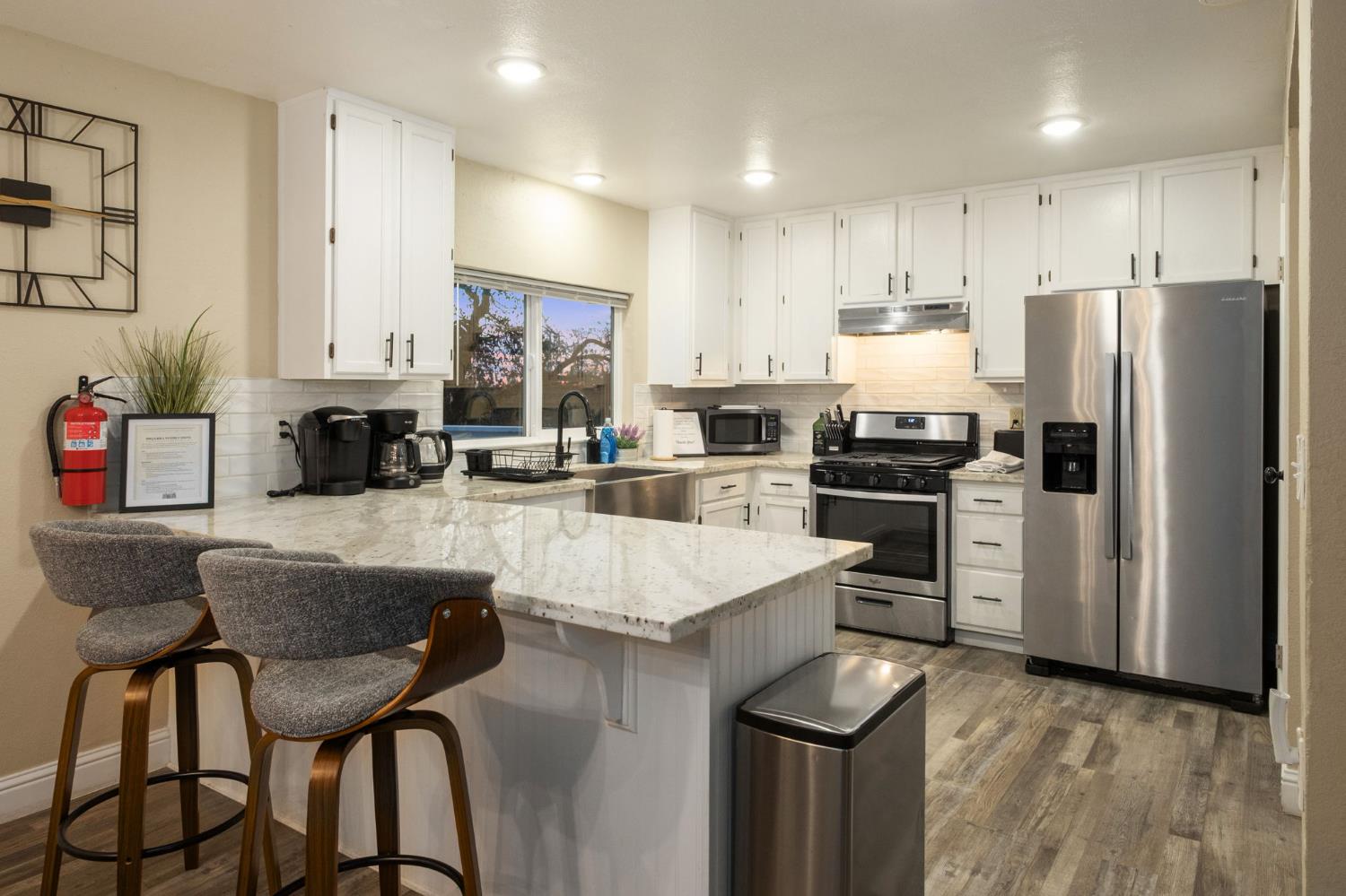 2811 East Westfall Road Mariposa, CA 95338 - Photo 8 of 25 a kitchen with a refrigerator a stove a sink and white cabinets with wooden floor
