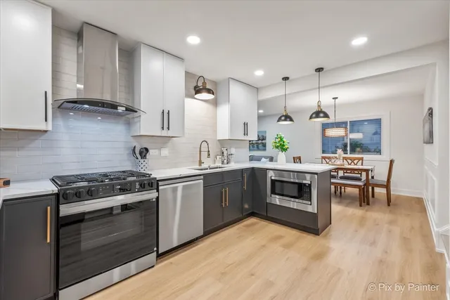 a kitchen with stainless steel appliances kitchen island granite countertop wooden floors a stove and a sink