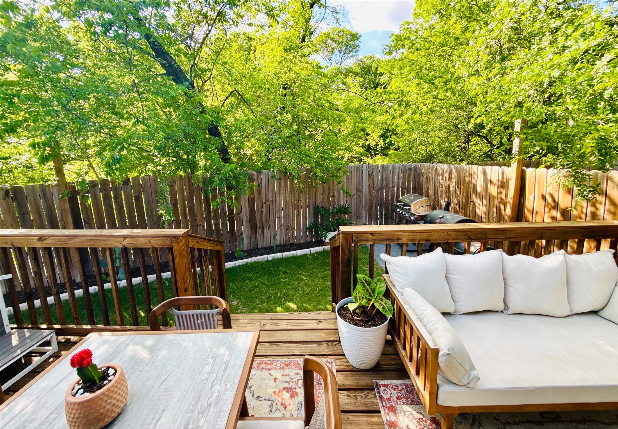 1616 Webberville Road, Unit A Austin, TX 78721 - Photo 6 of 35 The property features a wooden deck with railing, overlooking a fenced yard with a lawn and mature trees
