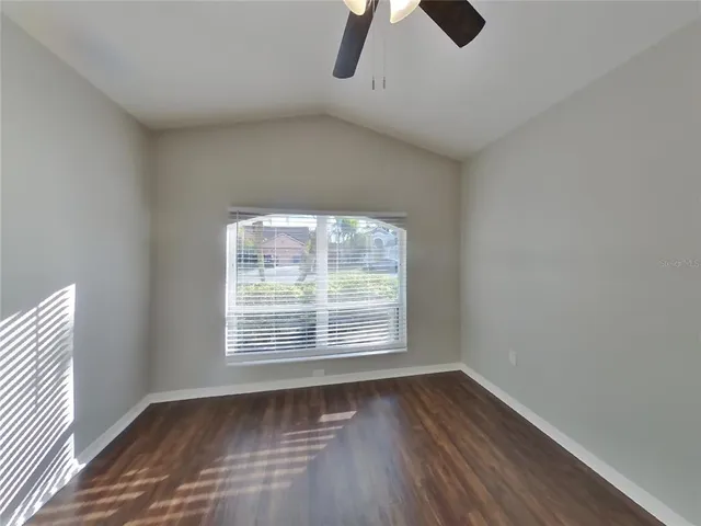 an empty room with wooden floor cabinet and windows