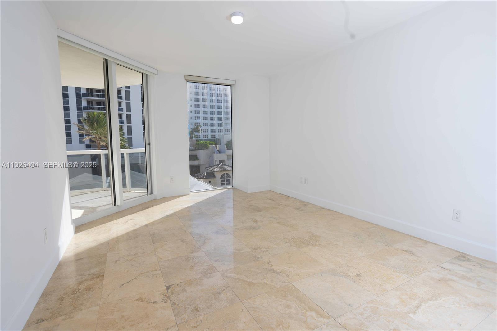 4779 Collins Avenue, Unit 504 Miami Beach, FL 33140 - Photo 22 of 45 an empty room with floor to ceiling window and windows