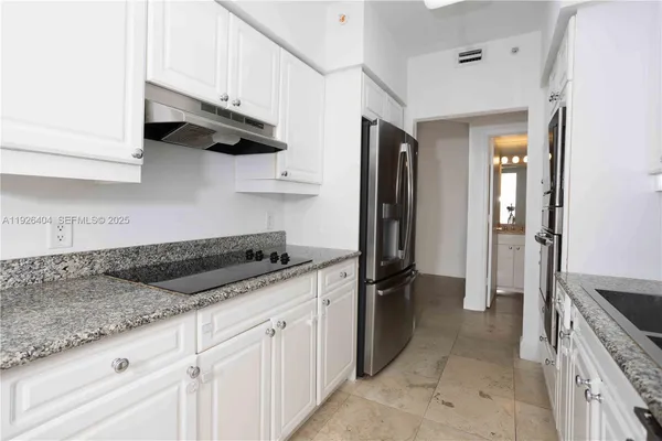 a kitchen with granite countertop a sink a stove and refrigerator