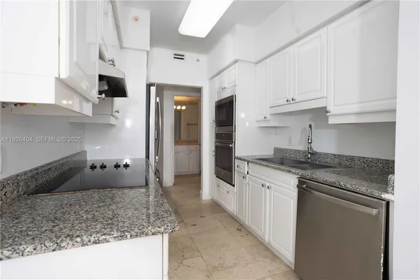 a kitchen with granite countertop a sink and white cabinets