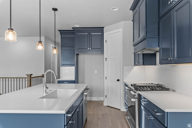 11673 South Halls Crk Road Draper, UT 84020 - Photo 12 of 22 Modern kitchen featuring blue cabinetry, light countertops, stainless steel appliances, and a white herringbone backsplash