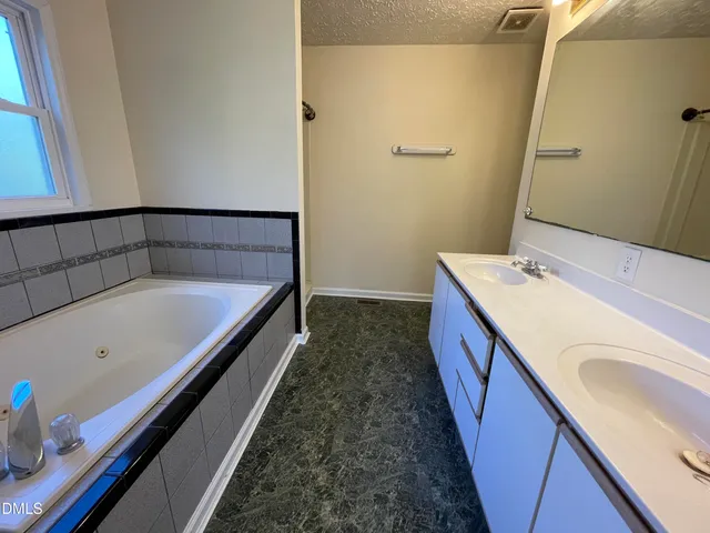 a bathroom with a tub sink and mirror