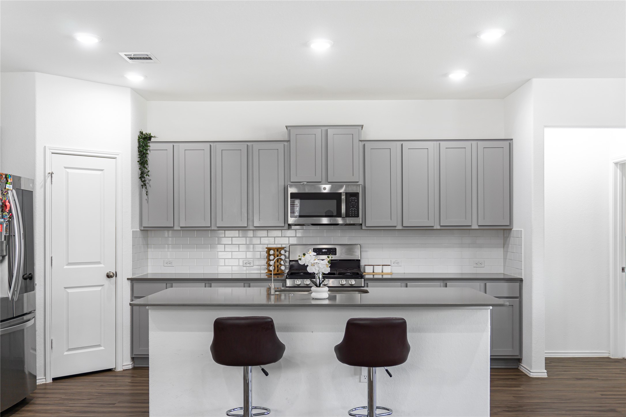 124 Cherry Ridge Road Georgetown, TX 78628 - Photo 9 of 23 Kitchen featuring grey shaker-style cabinetry, stainless steel appliances, white subway tile backsplash, and dark countertops