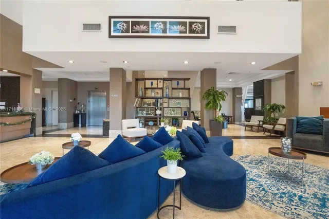 a living room with furniture potted plant and kitchen view