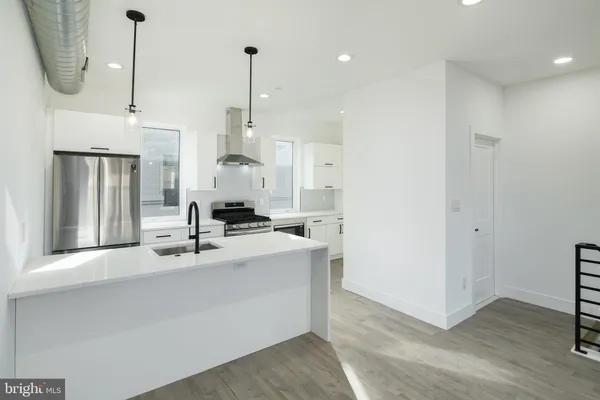 a kitchen with stainless steel appliances granite countertop a sink a refrigerator and a wooden floor