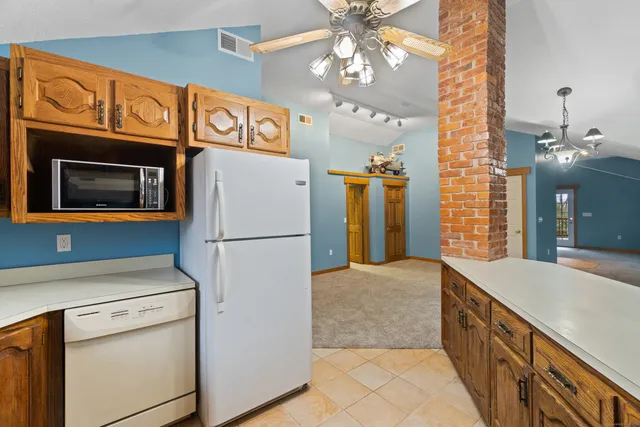 an empty room with chandelier fan and windows