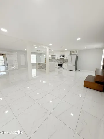 a large white kitchen with lots of counter space cabinets and a couch