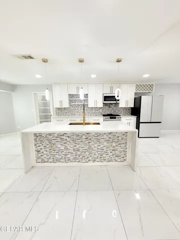 a kitchen with stainless steel appliances kitchen island granite countertop a stove a sink and a refrigerator