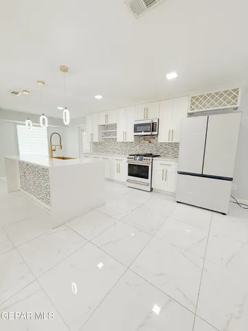 a large white kitchen with a sink and cabinets