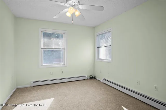 an empty room with windows and fan