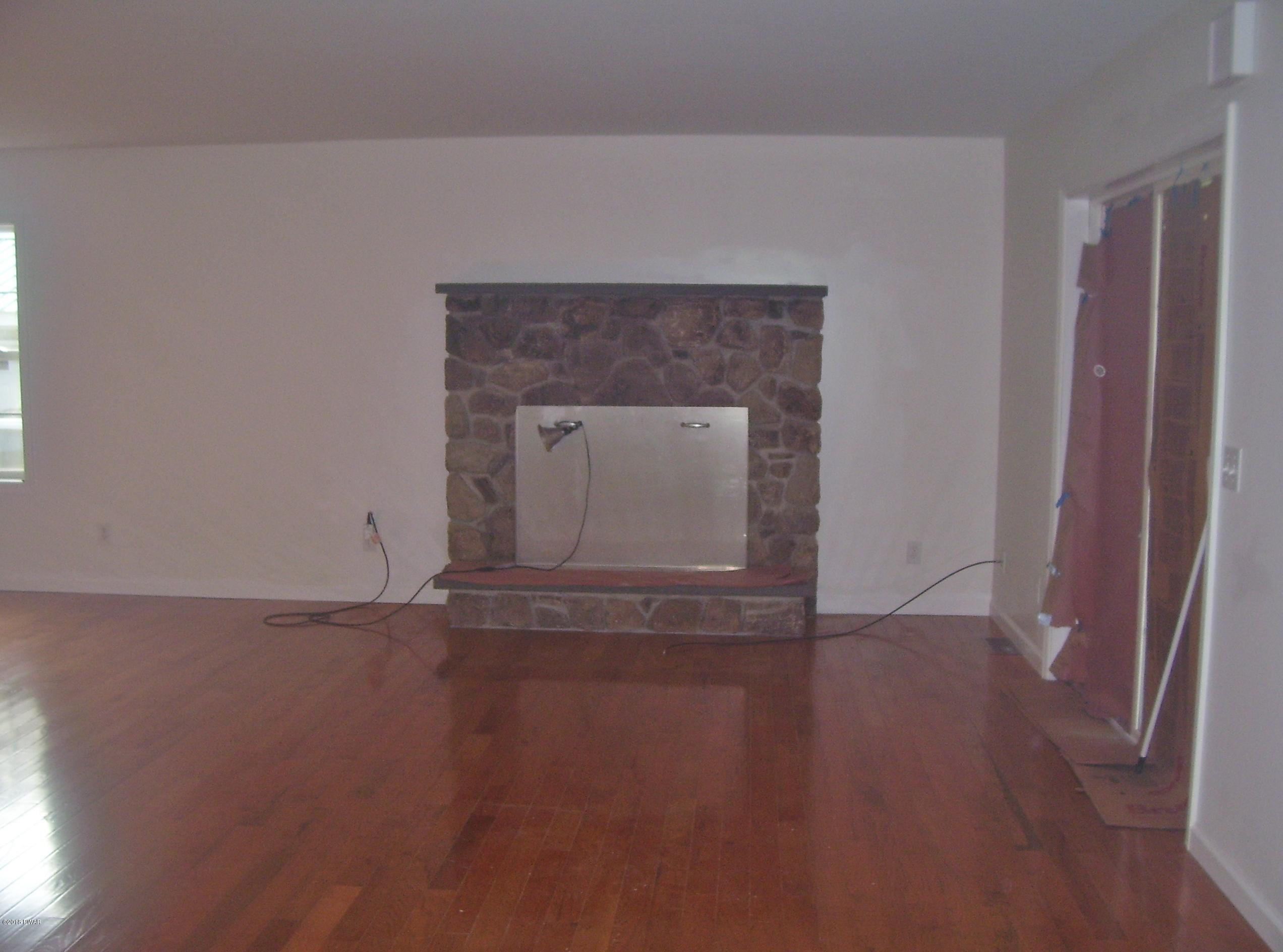 13 W Road Hawley, PA 18428 - Photo 9 of 26 a view of empty room with wooden floor and fireplace
