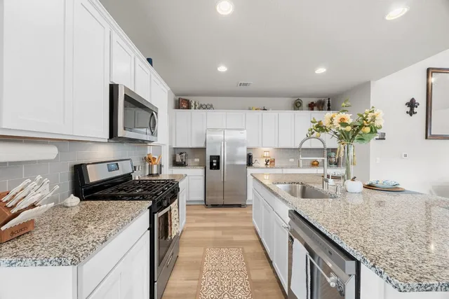 a kitchen with stainless steel appliances granite countertop a sink stove and refrigerator