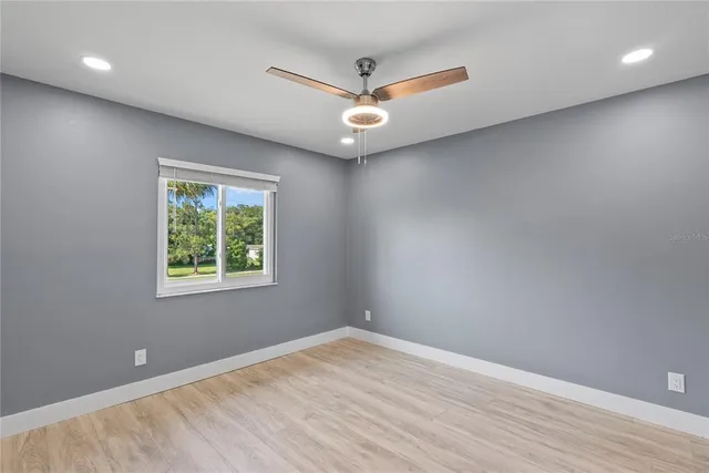 an empty room with wooden floor and a ceiling fan