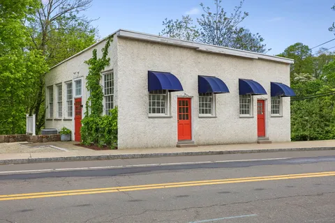 a view of a white house with large windows and a small yard