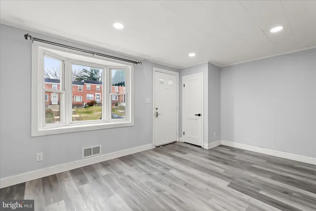 a view of an empty room with a window and wooden floor
