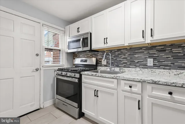 a kitchen with granite countertop white cabinets and white appliances