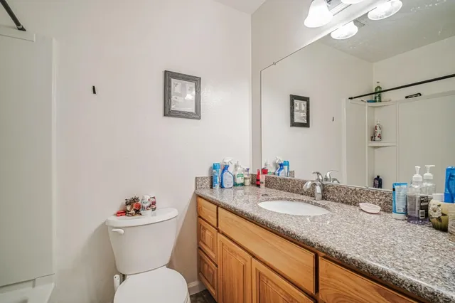 a bathroom with a granite countertop toilet sink and mirror