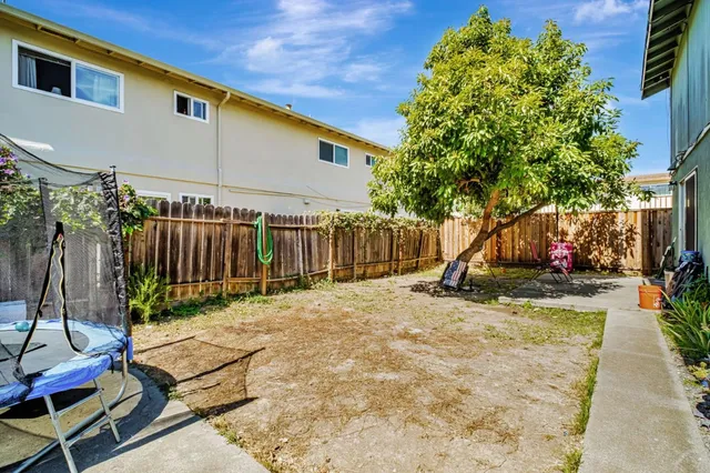 a view of backyard with wooden fence and a large tree