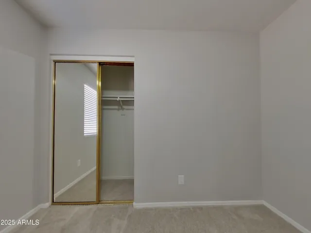 a view of an empty room with closet and a window
