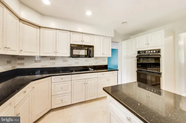 a kitchen with granite countertop a sink stove and white cabinets