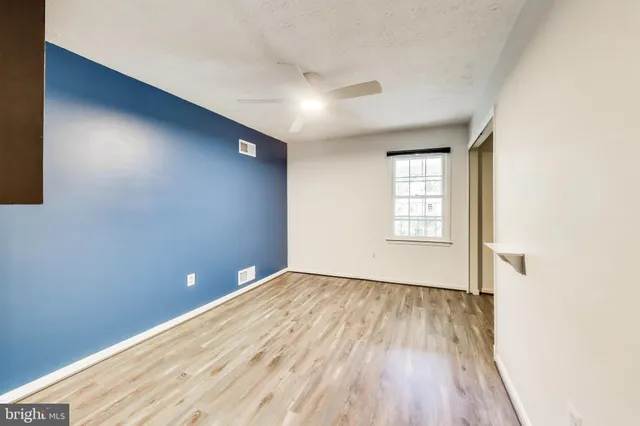 an empty room with wooden floor and windows