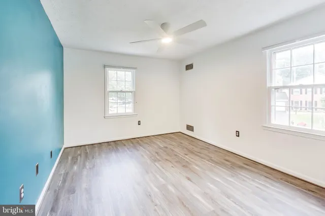 an empty room with wooden floor and windows